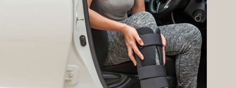 Woman wearing a cast, getting into a car.